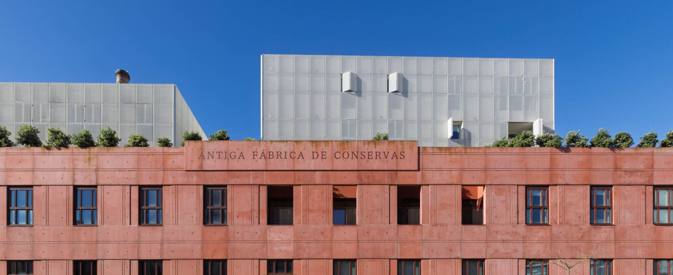 Fachada principal da Antiga Fábrica de Conservas em Matosinhos, betão pigmentado em terracota com cobertura em painéis metálicos perfurados