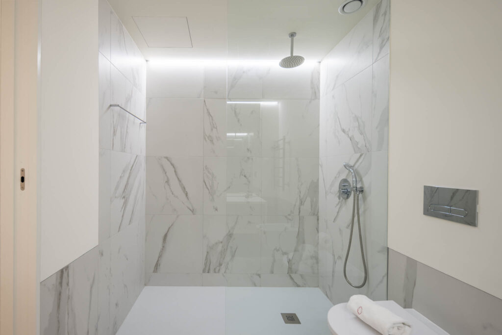 Duche amplo com revestimento a mármore branco e chuveiro de teto, casa de banho apartamento Home Me Matosinhos
