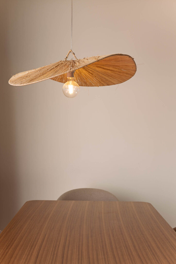 Candeeiro suspenso em fibra natural sobre mesa de jantar de madeira, detalhe de design de interiores Home Me