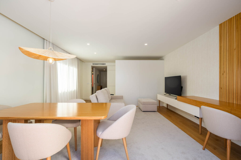 Sala de estar e jantar com mesa de madeira, candeeiro em fibra natural e painel de ripado, fotografia de interiores Matosinhos