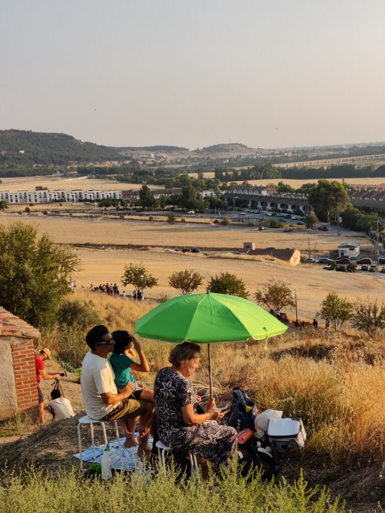 Observadores instalados com cadeiras e guarda-sol na encosta do Belén Viviente de Cabezón de Pisuerga durante o eclipse solar total de 2026