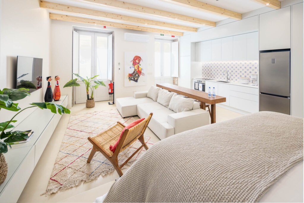 Fotografia de interiores de loft em open space em Viana do Castelo com vigas de madeira, sofá claro e cozinha com azulejo azul