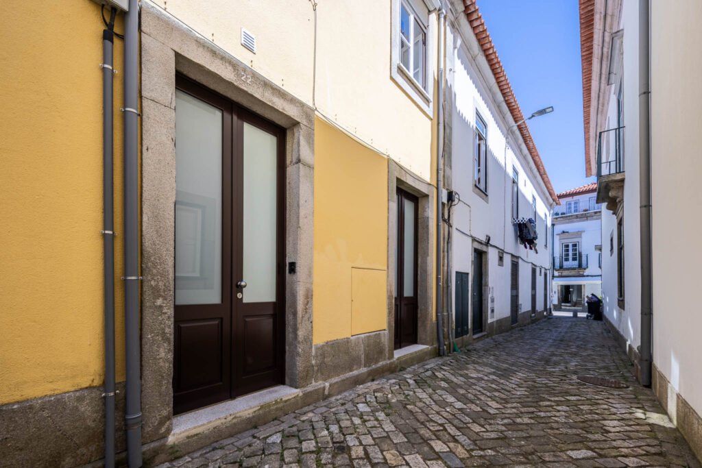 Rua estreita em calçada no centro histórico de Viana do Castelo com fachadas amarelas e portas em molduras de pedra