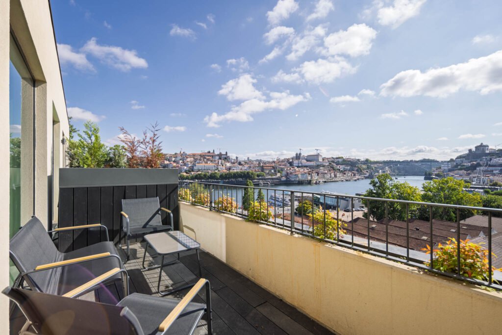 Varanda de alojamento local em Vila Nova de Gaia com cadeiras de exterior e vista para o rio Douro e o Porto