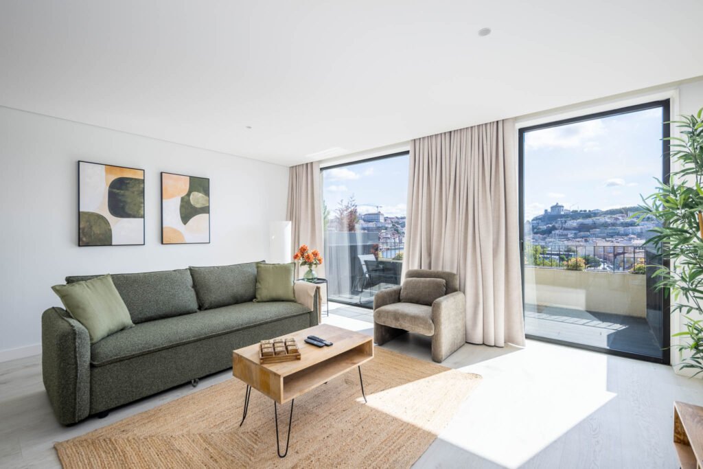 Sala luminosa com sofá verde, mesa de centro em madeira e vista para o Porto