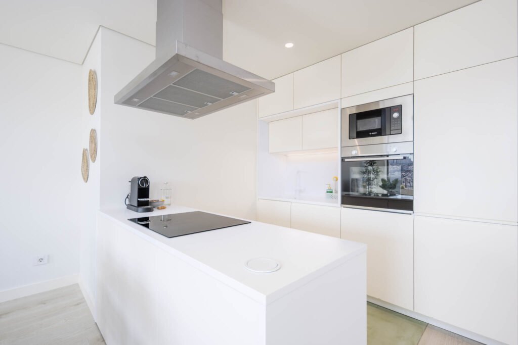 Pormenor da cozinha com placa, máquina de café e colunas de forno e micro-ondas