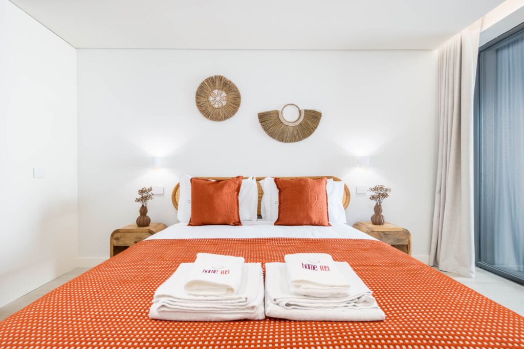 Fotografia de alojamento local: quarto com manta terracota, cama em madeira e peças decorativas circulares na parede