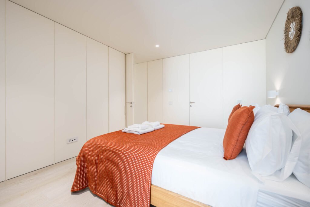 Quarto com roupeiro branco embutido e almofadas terracota