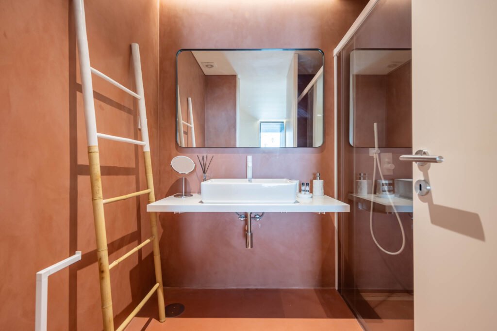 Fotografia de alojamento local: casa de banho com paredes terracota, lavatório branco e escada decorativa